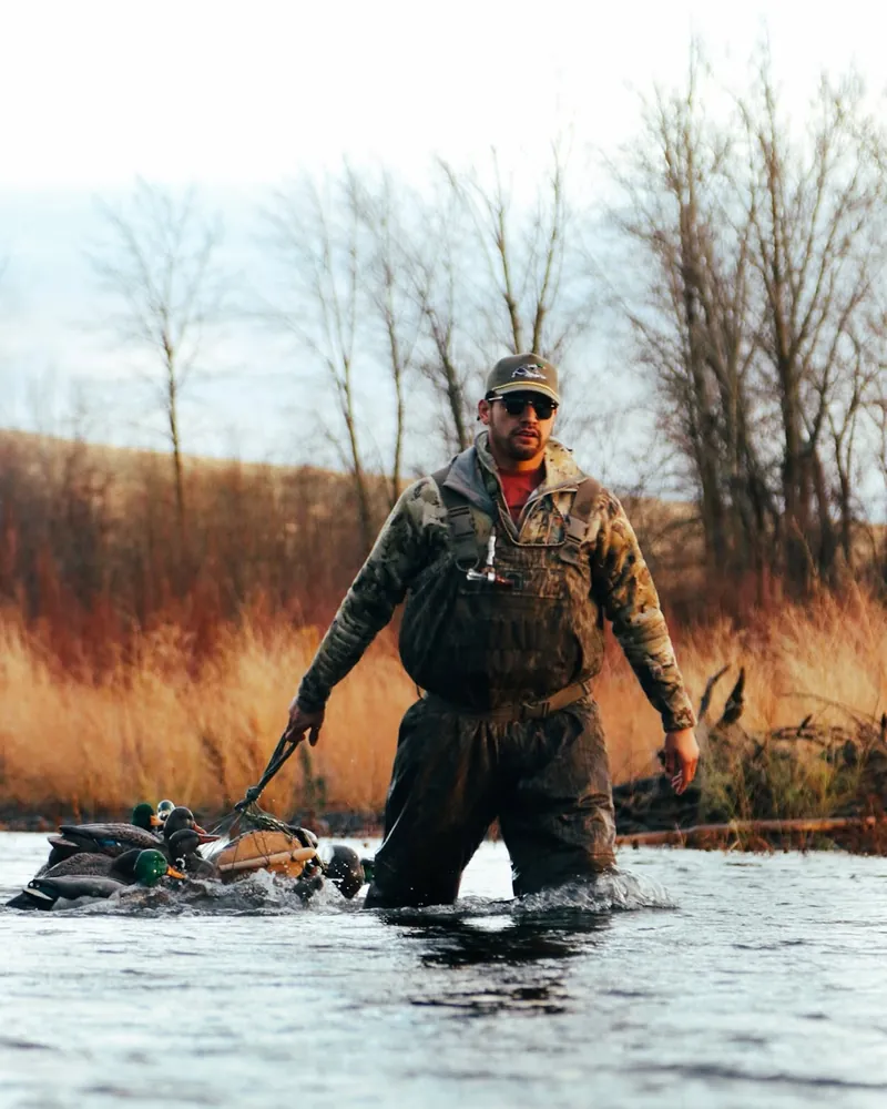 Phoenix wading through a river with a bag of decoys