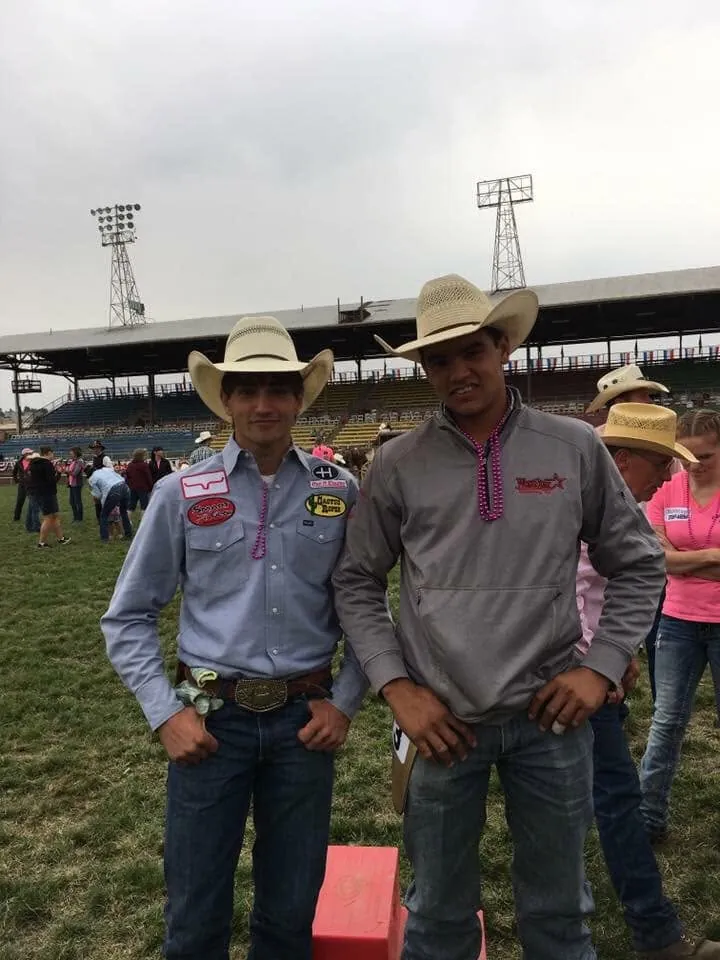 Two teenage rodeo competitors standing at a stadium